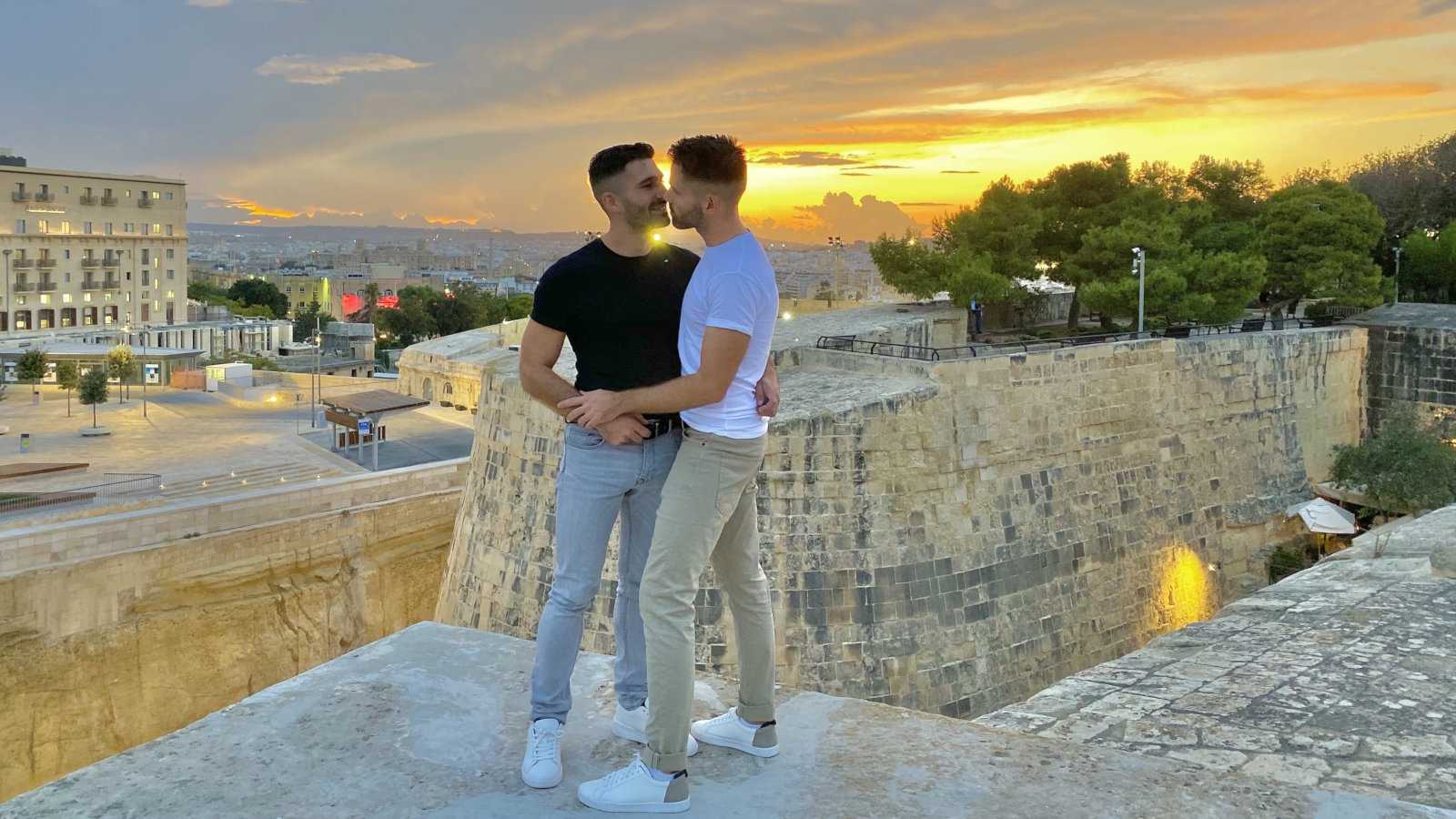 Gay couple kissing in Valletta, Malta at sunset.